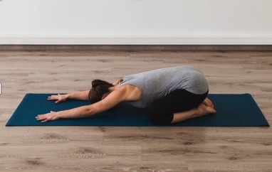 woman in grey and black sportwear doing the child's pose