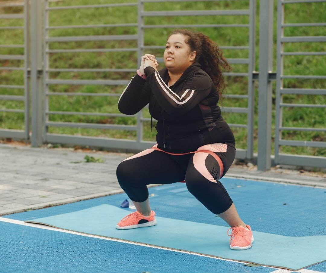 woman doing squats using a resistance band outdoors