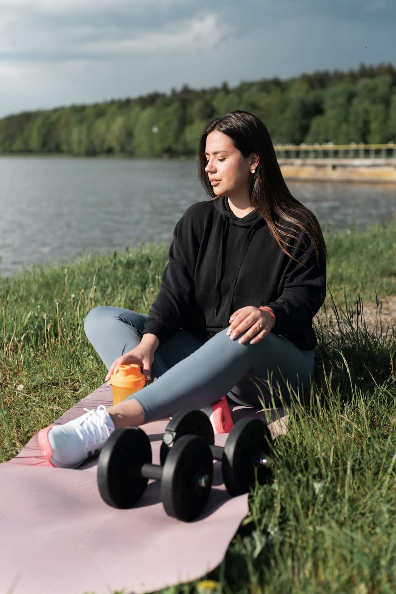 Woman-Sitting-on-Pink-Yoga-Mat-Near-the-River