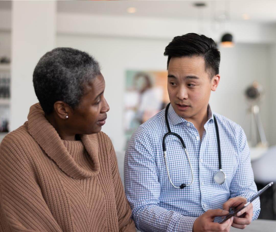 a woman talking to her doctor who is holding a tablet