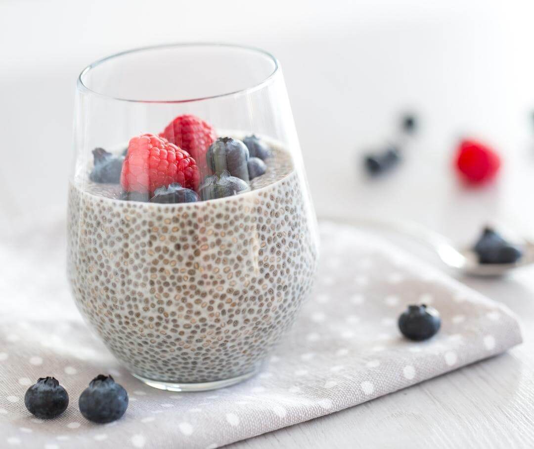 glass full of chia seeds soaked in almond milk with berries on top