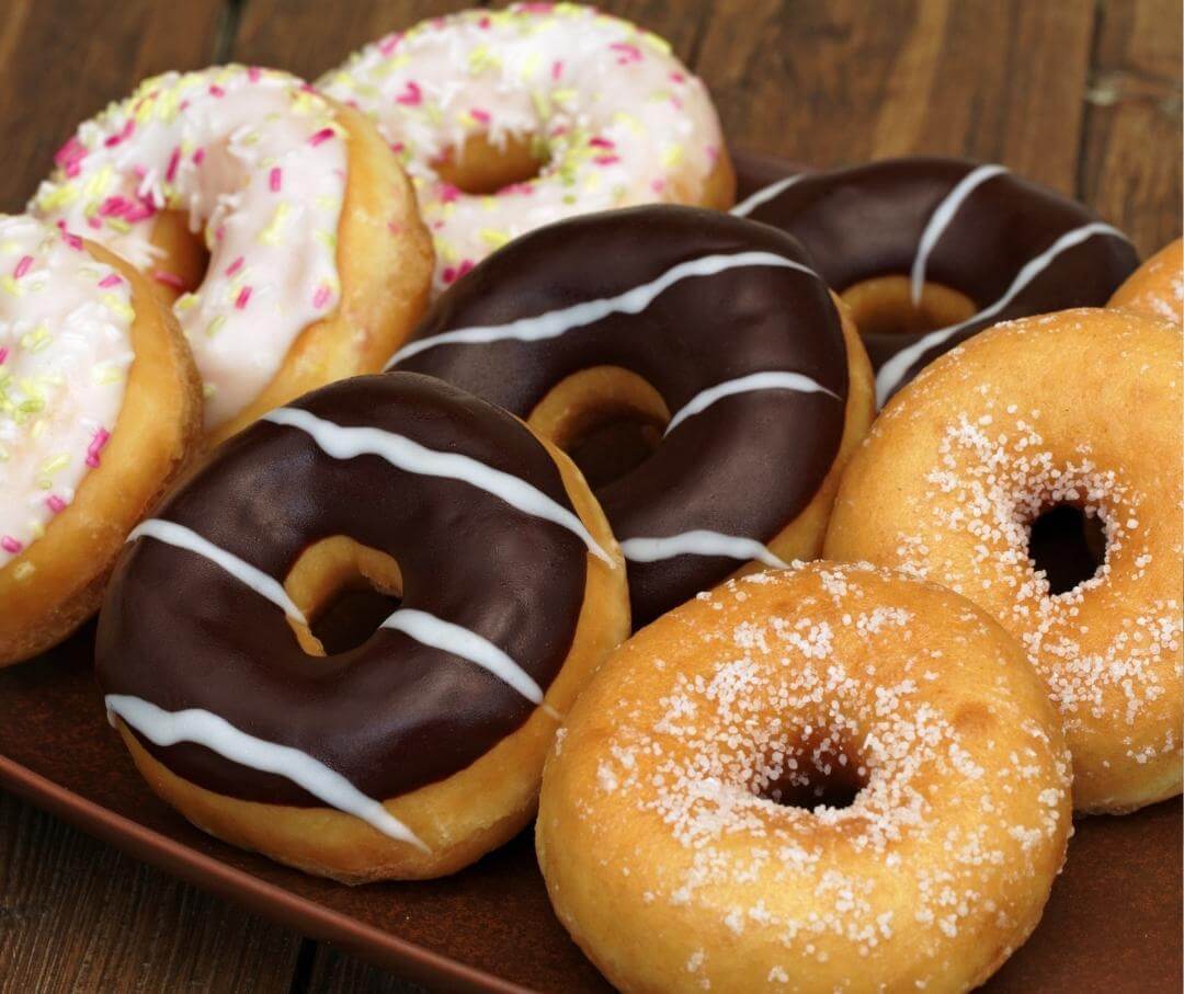 a selection of frosted donuts on a wooden table