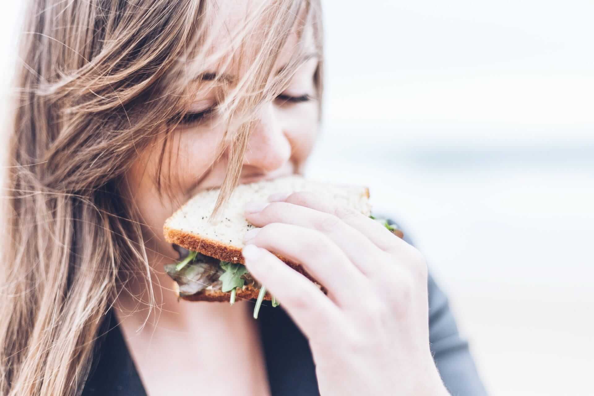 Young-woman-enjoying-a-convenient-sandwich-how-to-eat-slower