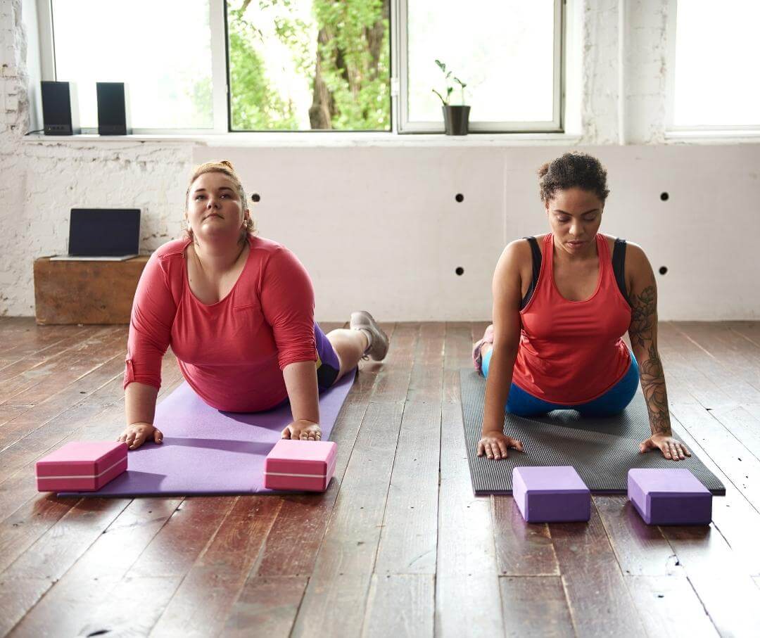 two women doing cobra pose on yoga mats