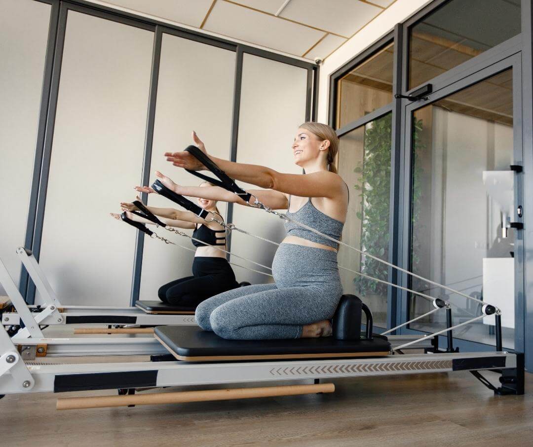 two pregnant women doing pilates in a studio