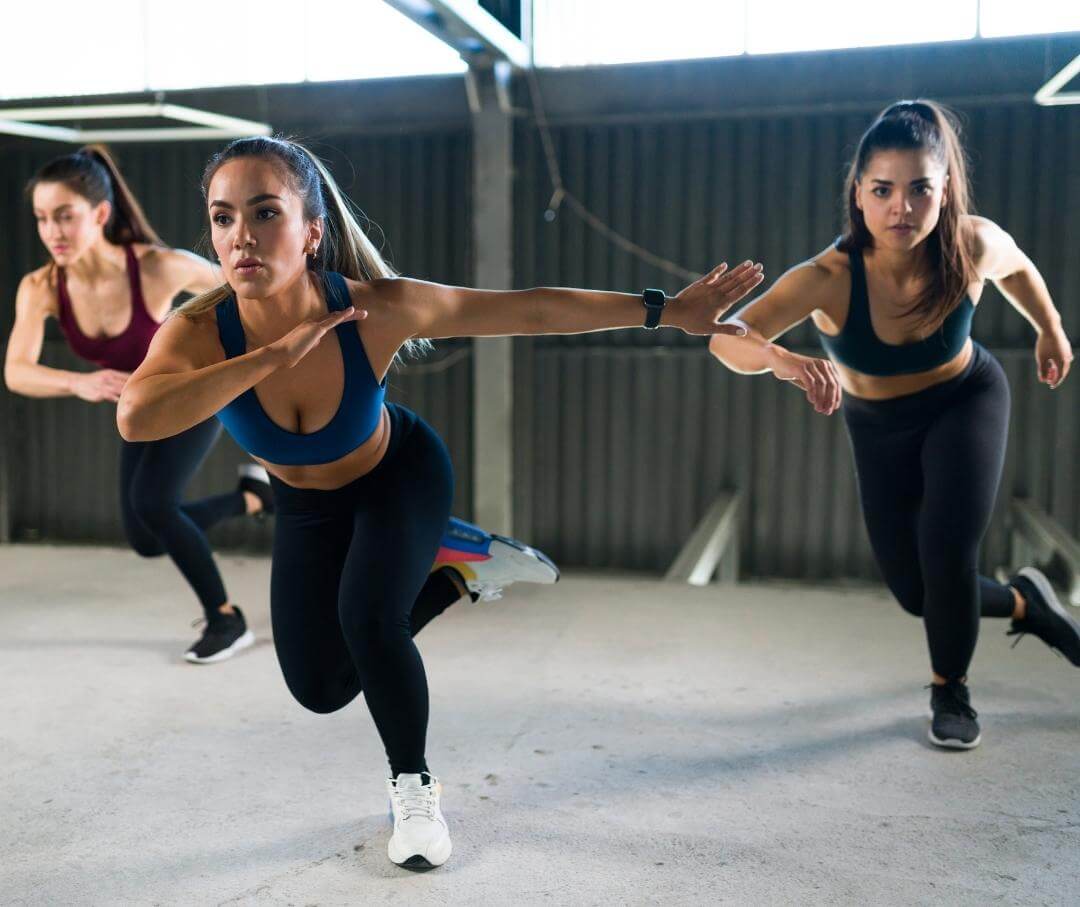 3 women practicing lateral bounds in HIIT workout class