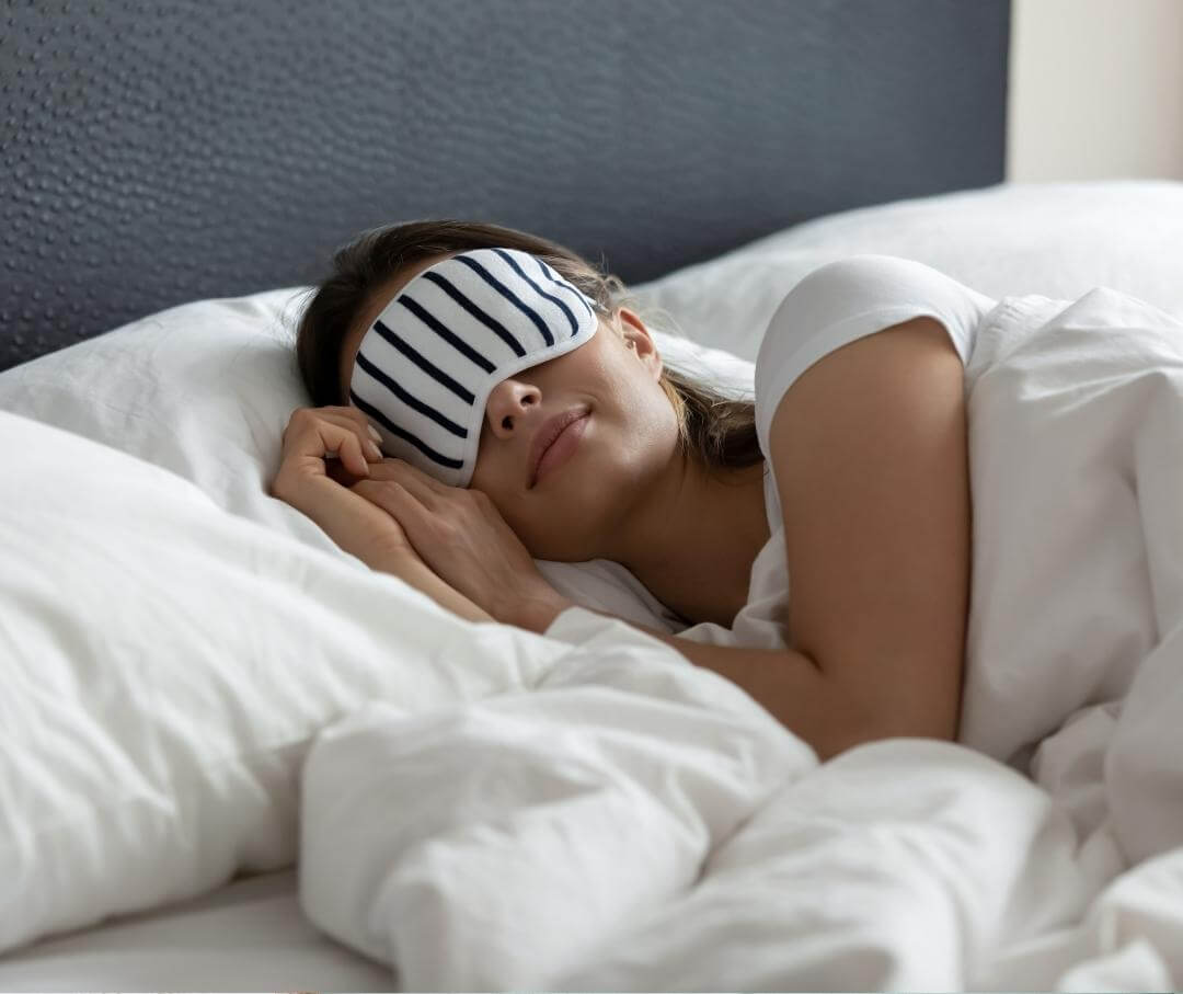 woman wearing a striped sleeping mask in bed