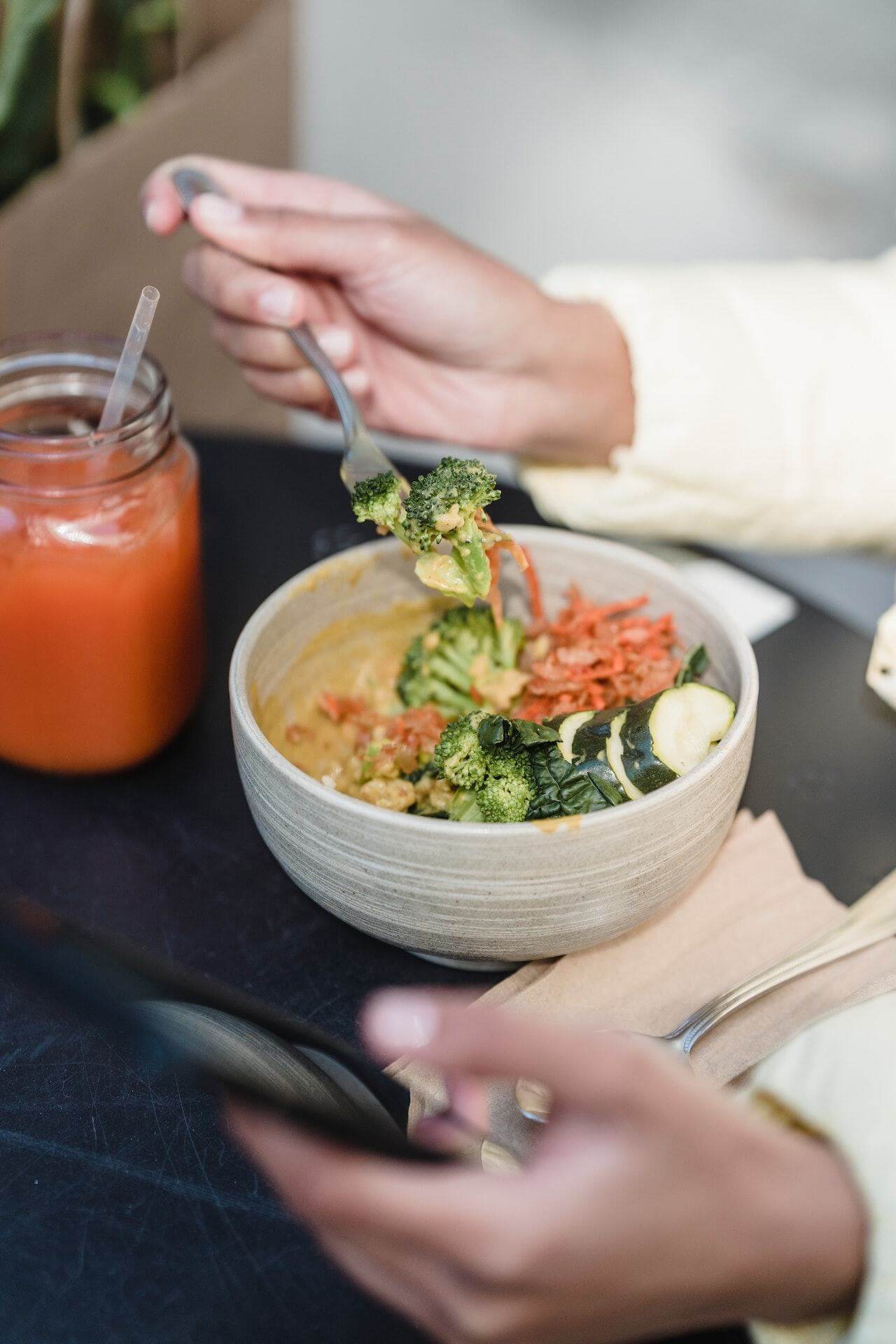 close-up-of-hand-holding-fork-eating-healthy-bowl-with-smoothie