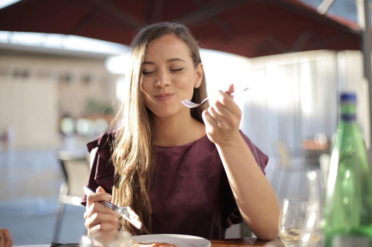 woman-enjoying-her-food-outdoors-smiling