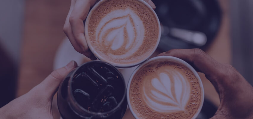 Three friends holding coffee cups together during a "cheers"