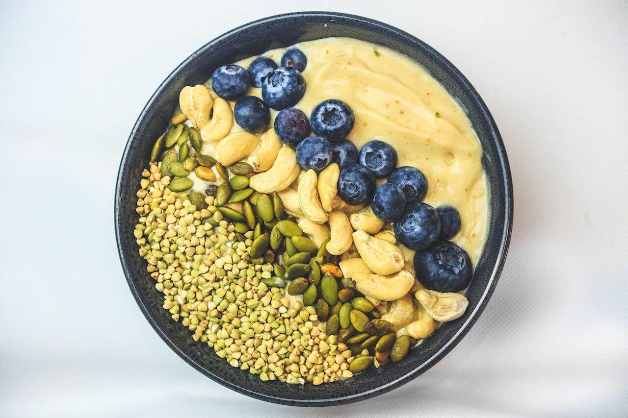 acai-bowl-with-nuts-and-blueberries-on-white-surface