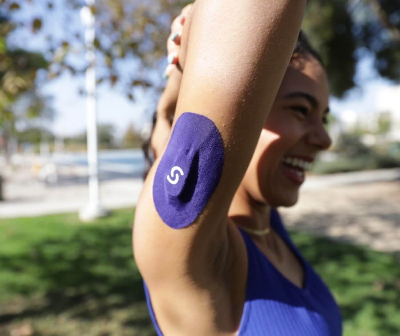 Woman smiling and wearing a CGM on her right arm