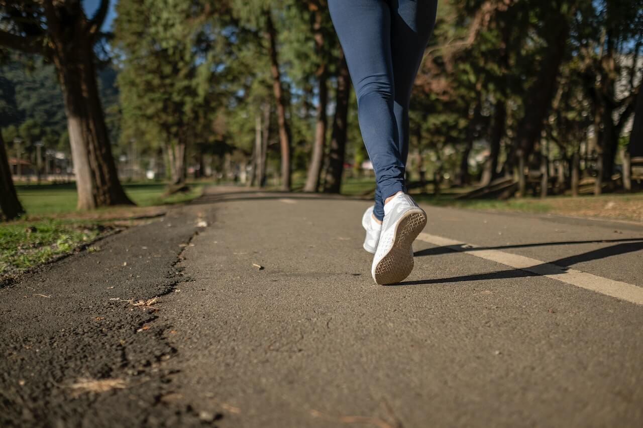 person-in-blue-denim-jeans-and-white-sneakers-walking-on-road