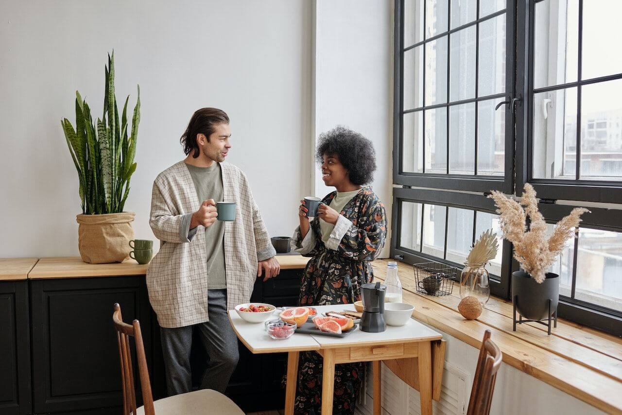 Man-and-woman-in-kitchen-with-fruit-and-coffee-in-the-morning-happy