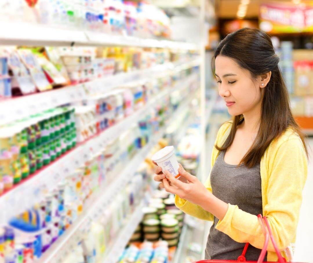 woman looking at different yogurts in a grocery store