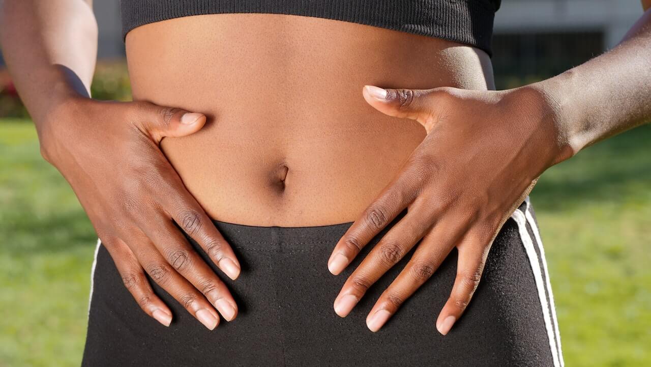 woman in sports clothes with her hands on her belly