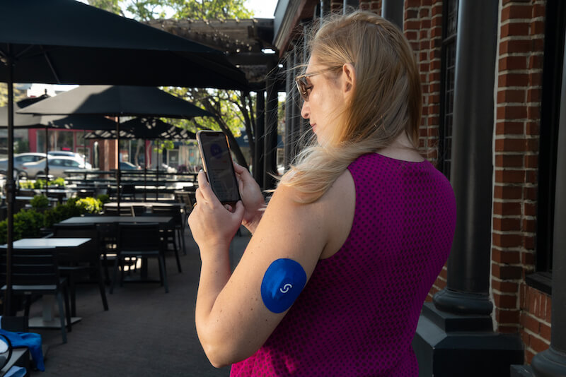 Woman using the Signos app and wearing a CGM plus Signos sport cover