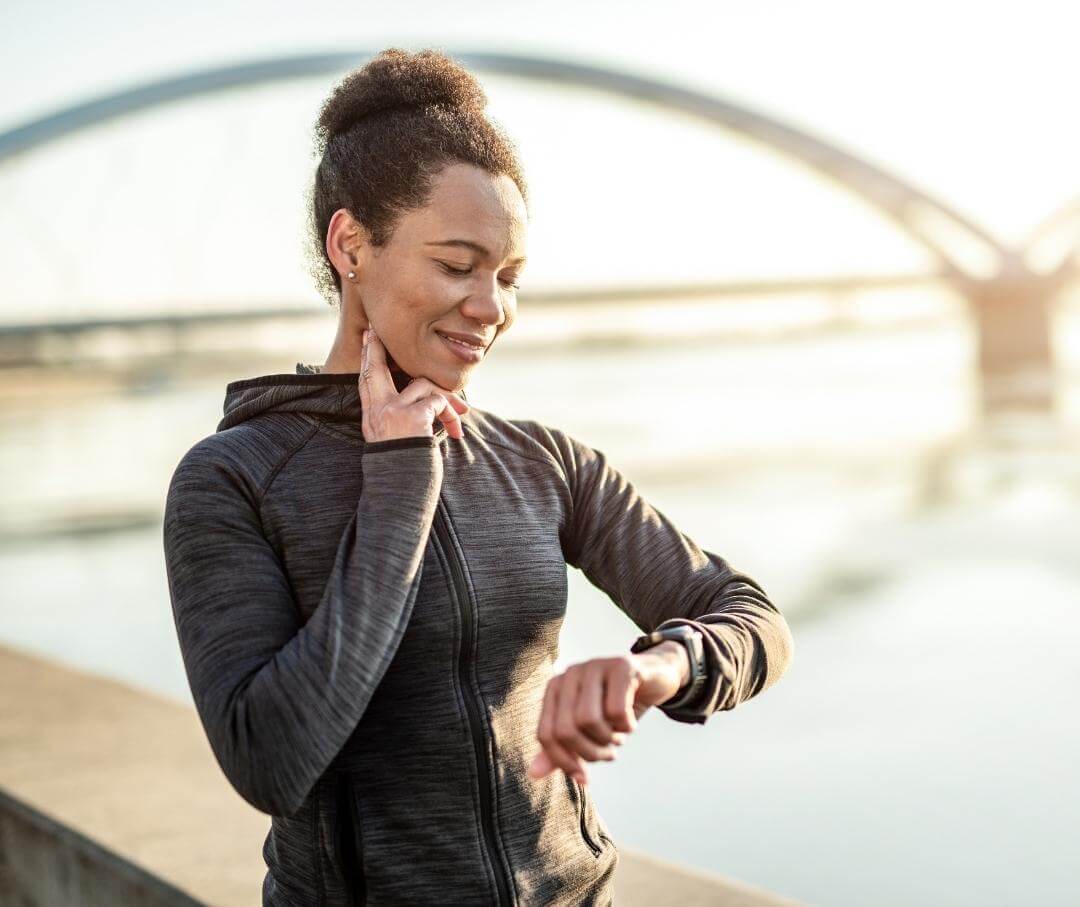 a woman wearing workout clothes and taking her pulse