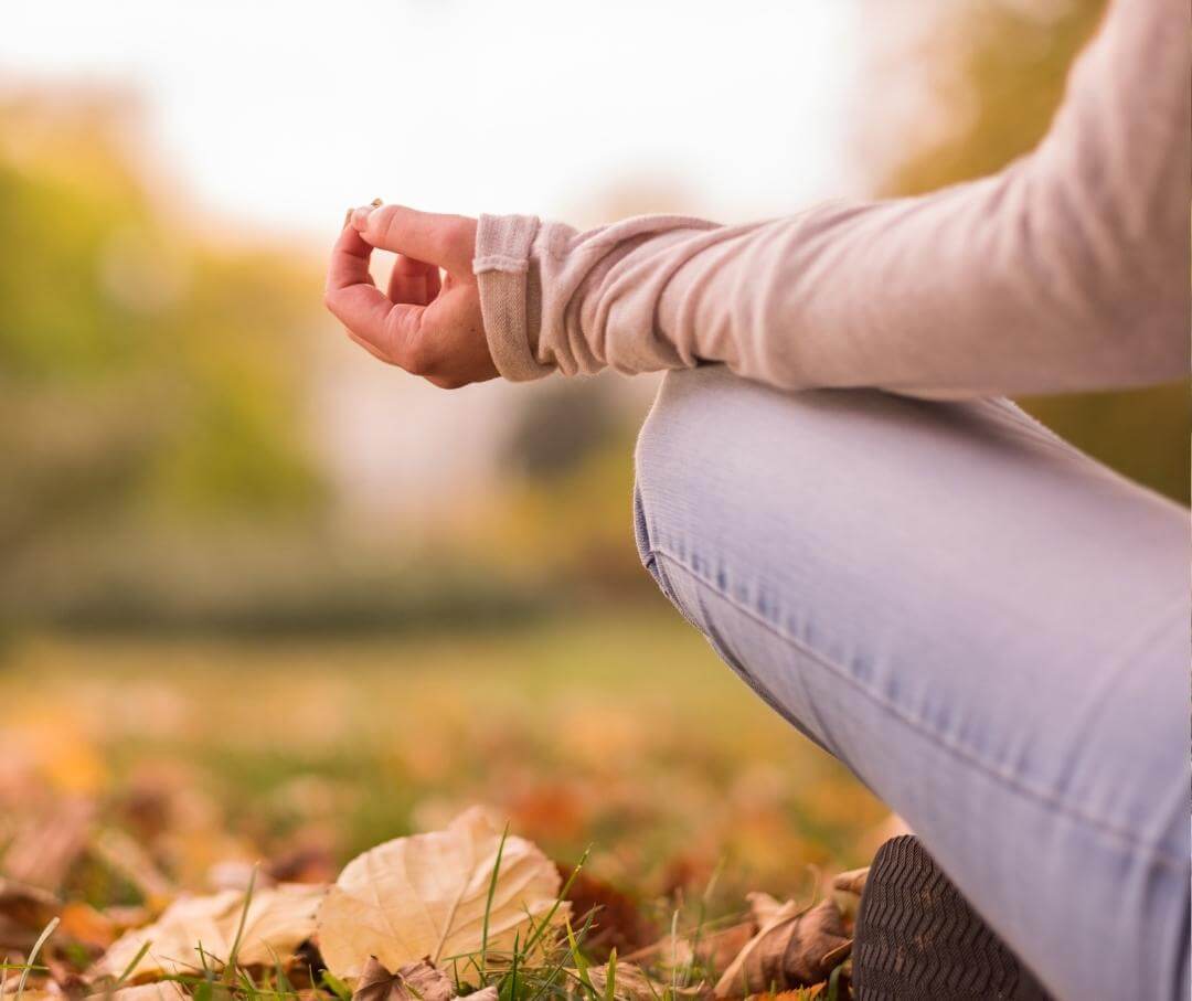 person sitting cross-legged with hand in meditative position