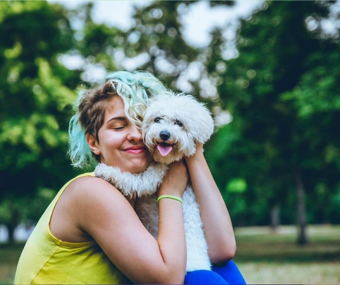 Woman hugging her white dog outdoors