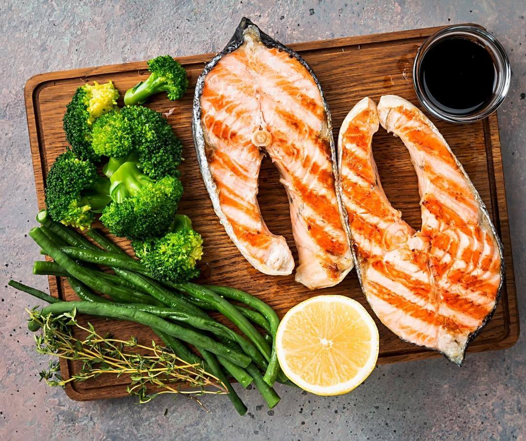 two salmon steaks on a cutting board with lemon and herbs