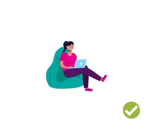 Person sitting cross-legged on a bean bag chair while working on computer