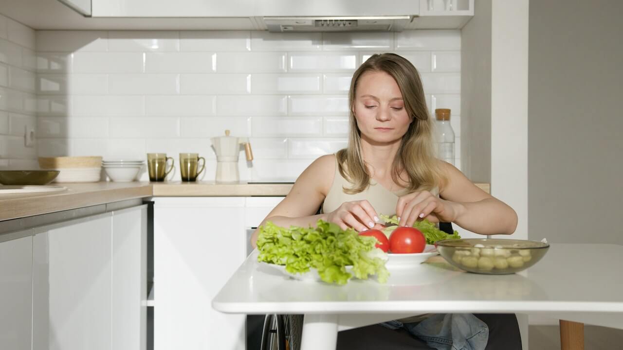 woman-in-brown-tank-top-sitting-on-kitchen-table-with-vegetable-on-top