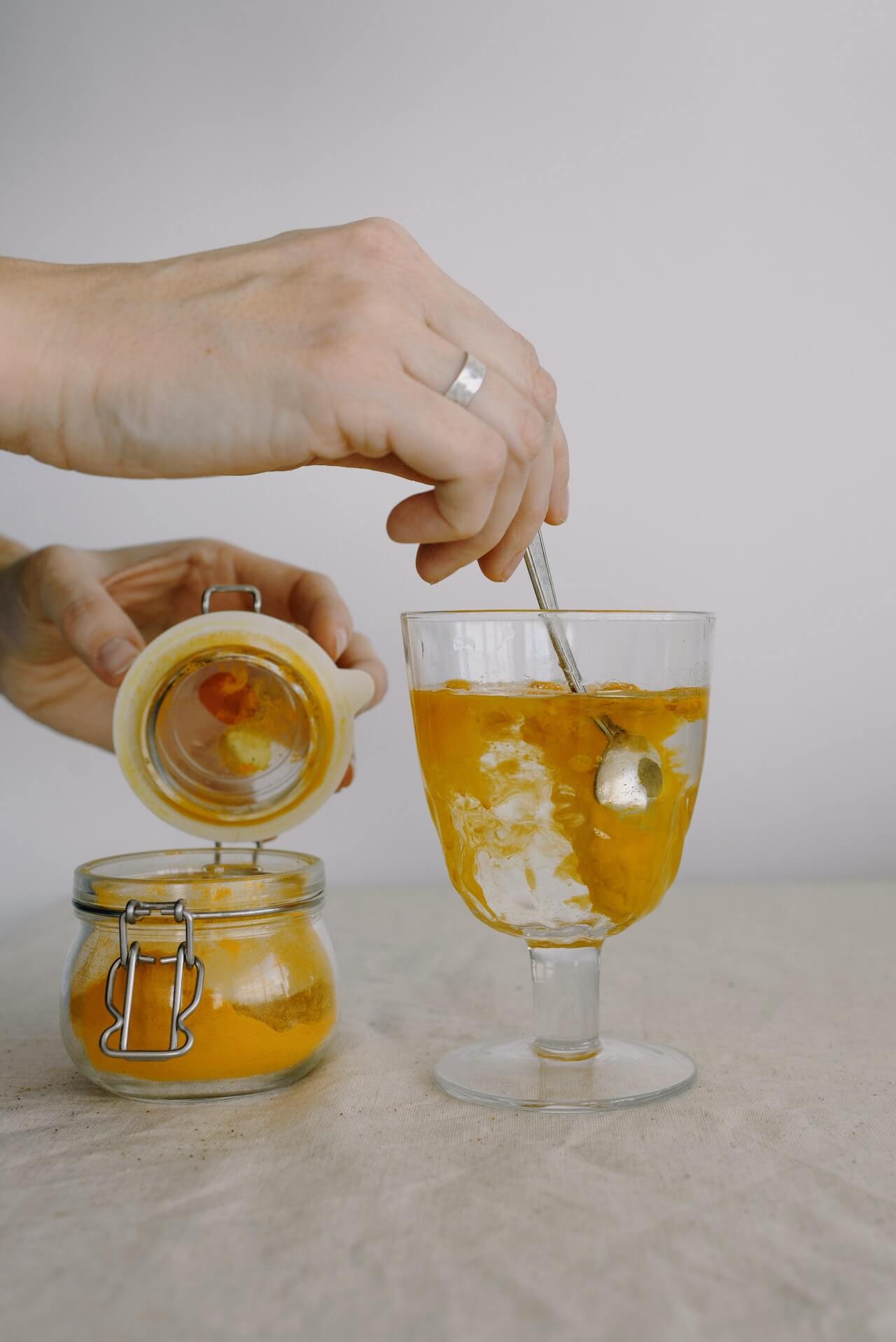 person adding turmeric in glass of hot water