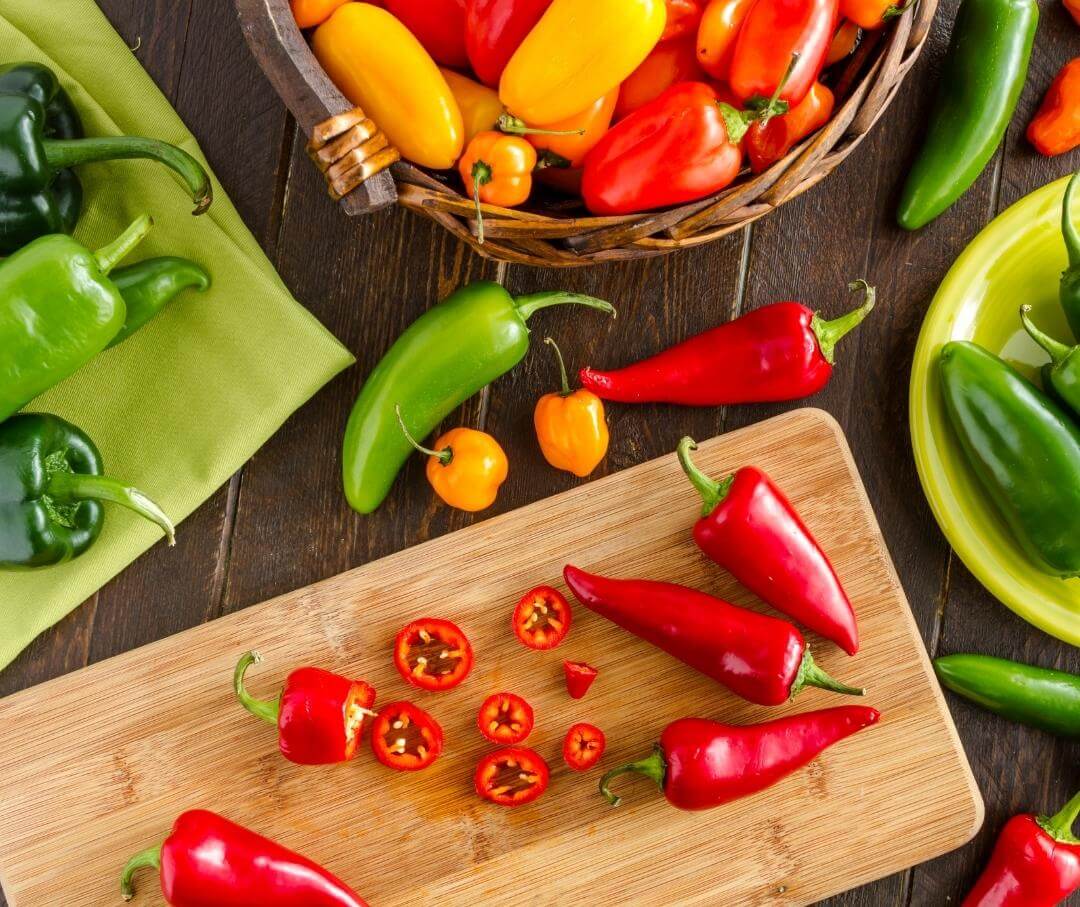 a variety of chili peppers on a wood table