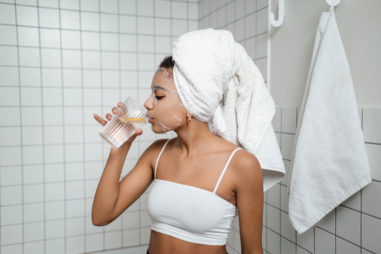 young-woman-taking-a-sip-of-water-while-using-a-face-mask