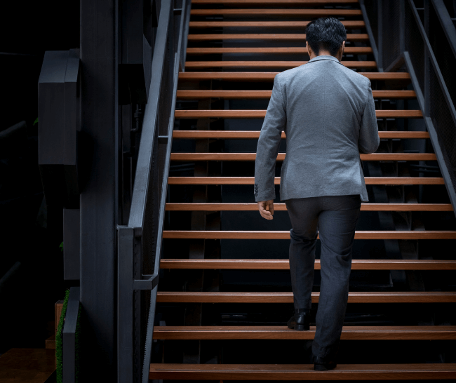 Man, dressed in business casual clothing, walking up a flight of stairs